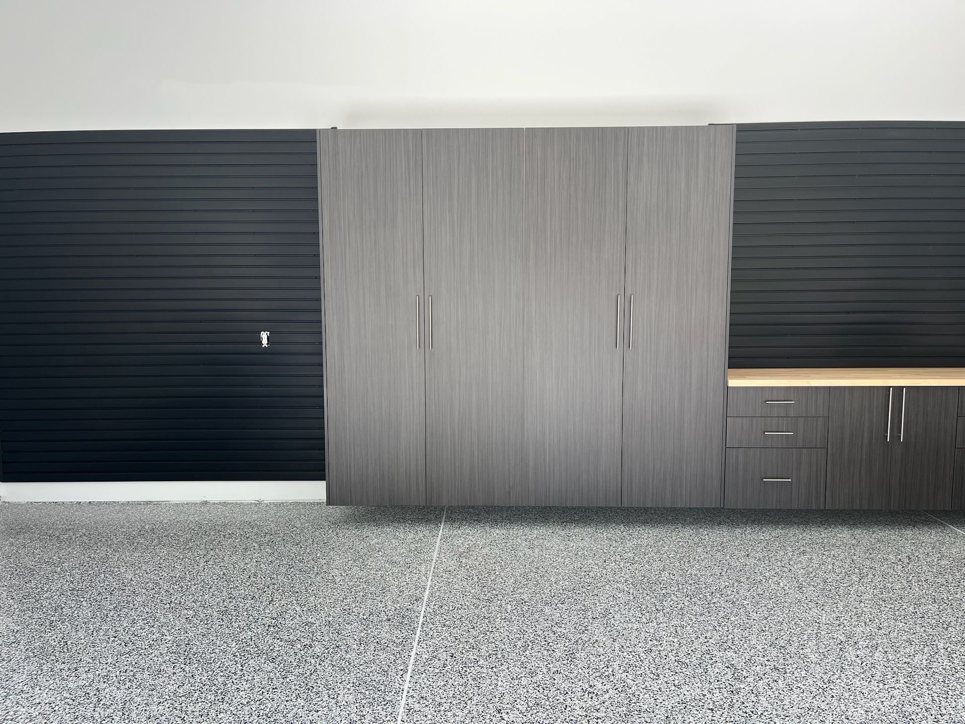 Modern kitchen cabinets with dark side panels, wood center section, and speckled stone floor