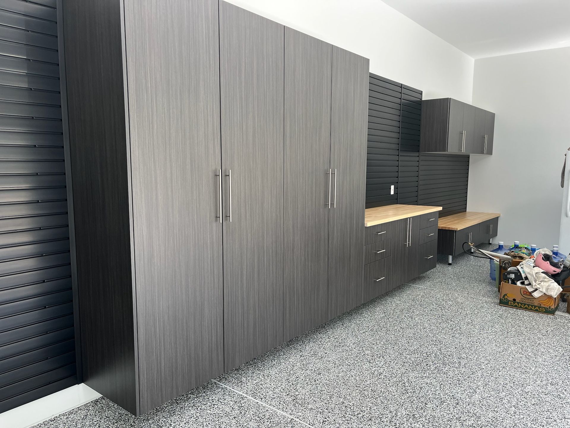 Modern kitchen with dark wood cabinets, light countertop, and speckled gray floor, with boxes on the right.