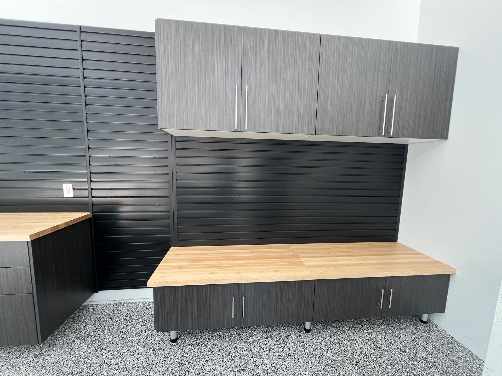 Office kitchenette with gray cabinets, wood countertops, and a black slatted backsplash