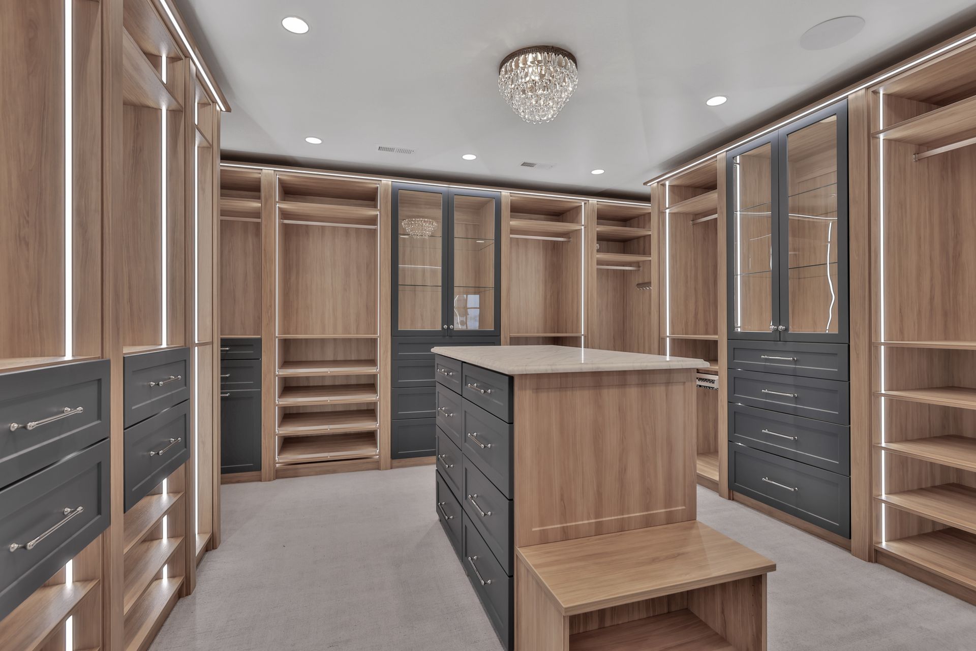 Walk-in closet with wood shelves, drawers, and an island under recessed lighting