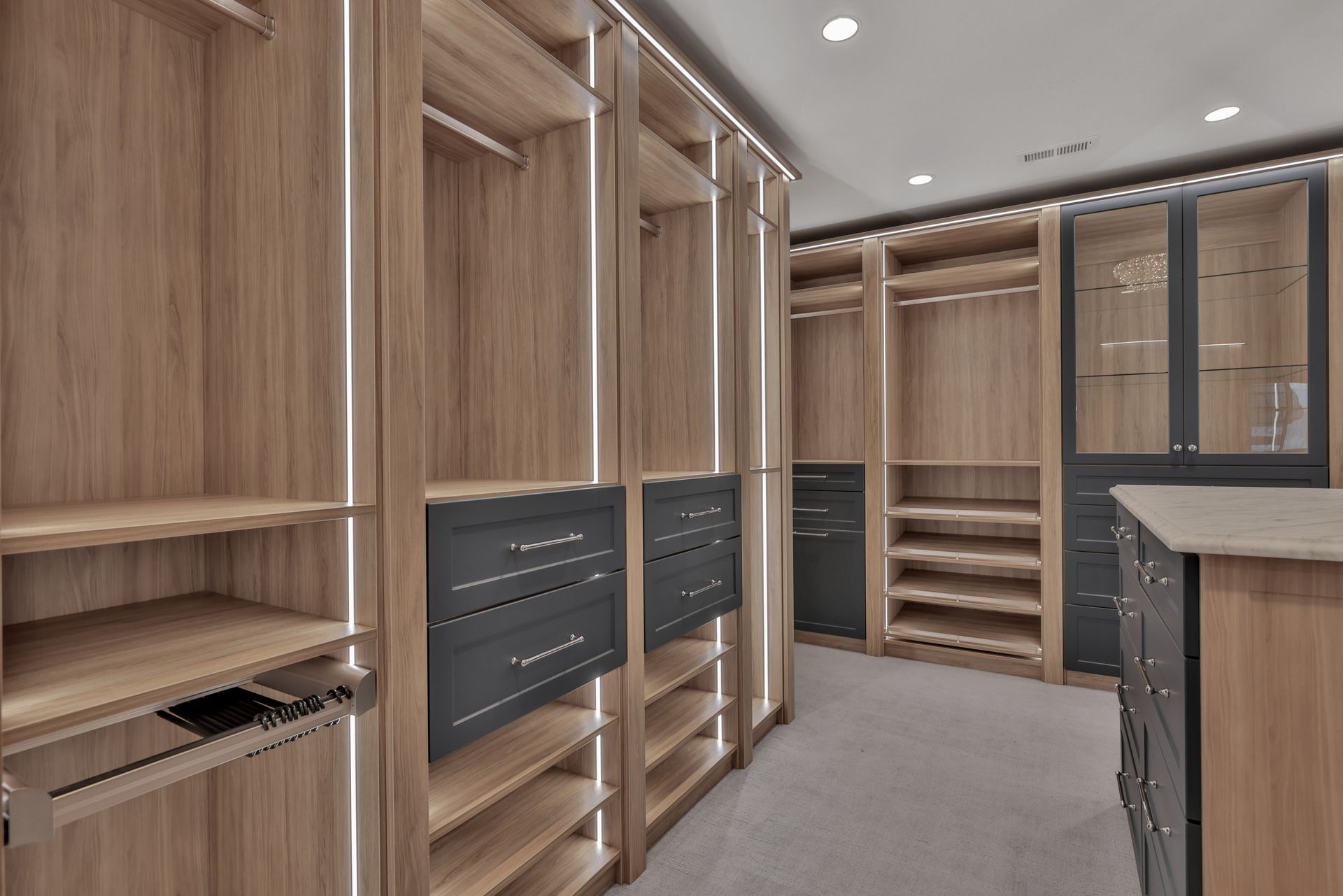 Walk-in closet with wood cabinetry, black drawer fronts, and shelves under recessed ceiling lights
