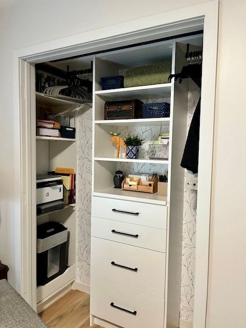 Open closet with shelves, drawers, clothes, and storage bins in a bedroom closet organizer