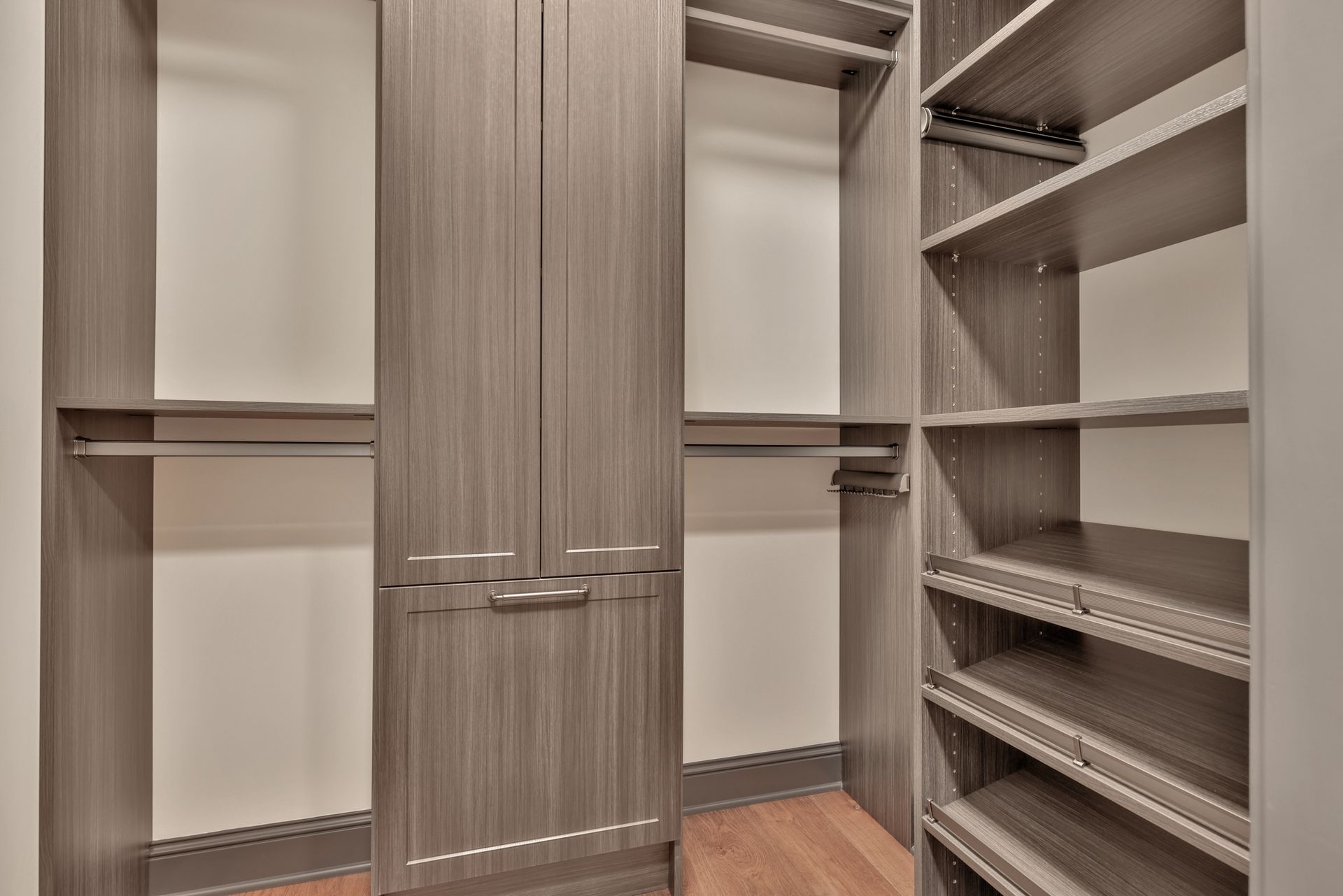Empty walk-in closet with wood cabinets, white shelves, and hanging rods