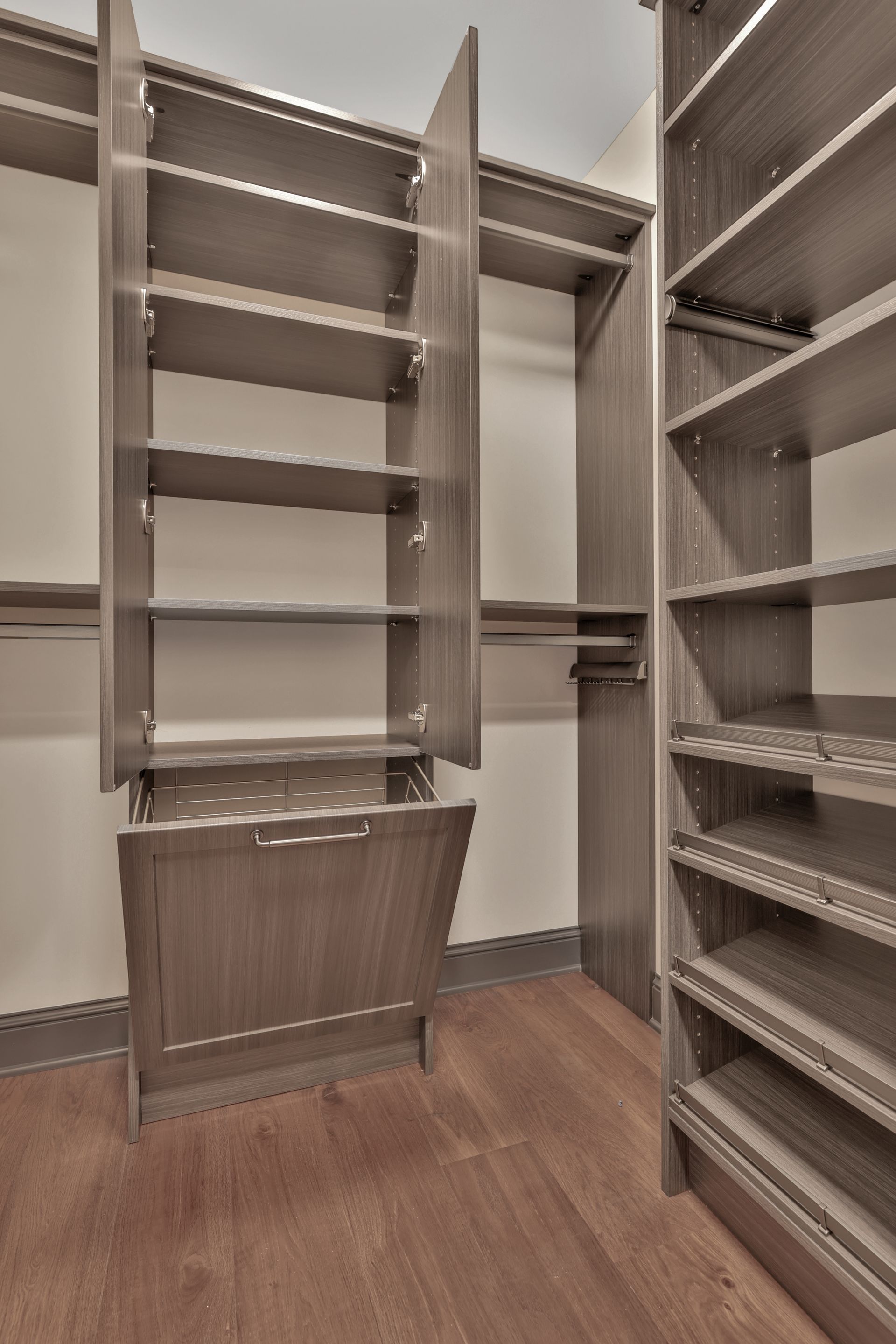 Walk-in closet with built-in shelves, hanging space, and wood floors, viewed through open doors