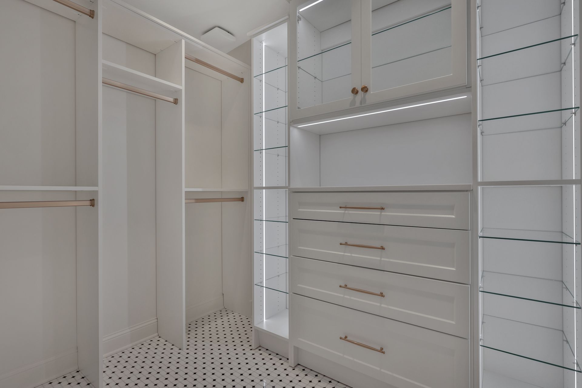 Walk-in closet with white built-in shelves, drawers, hanging rods, and patterned floor tiles