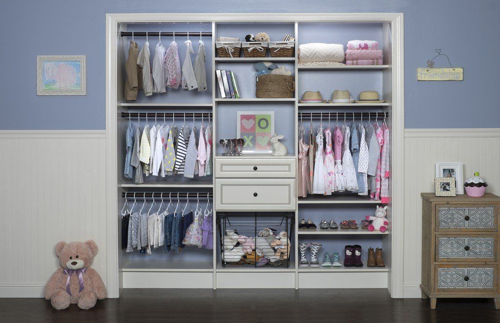 a teddy bear is sitting in front of a closet filled with clothes .