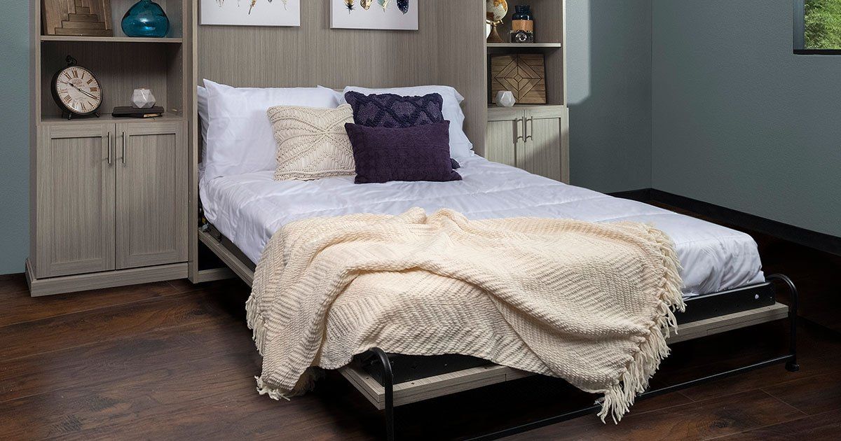 a murphy bed with a blanket on it is sitting in a room .