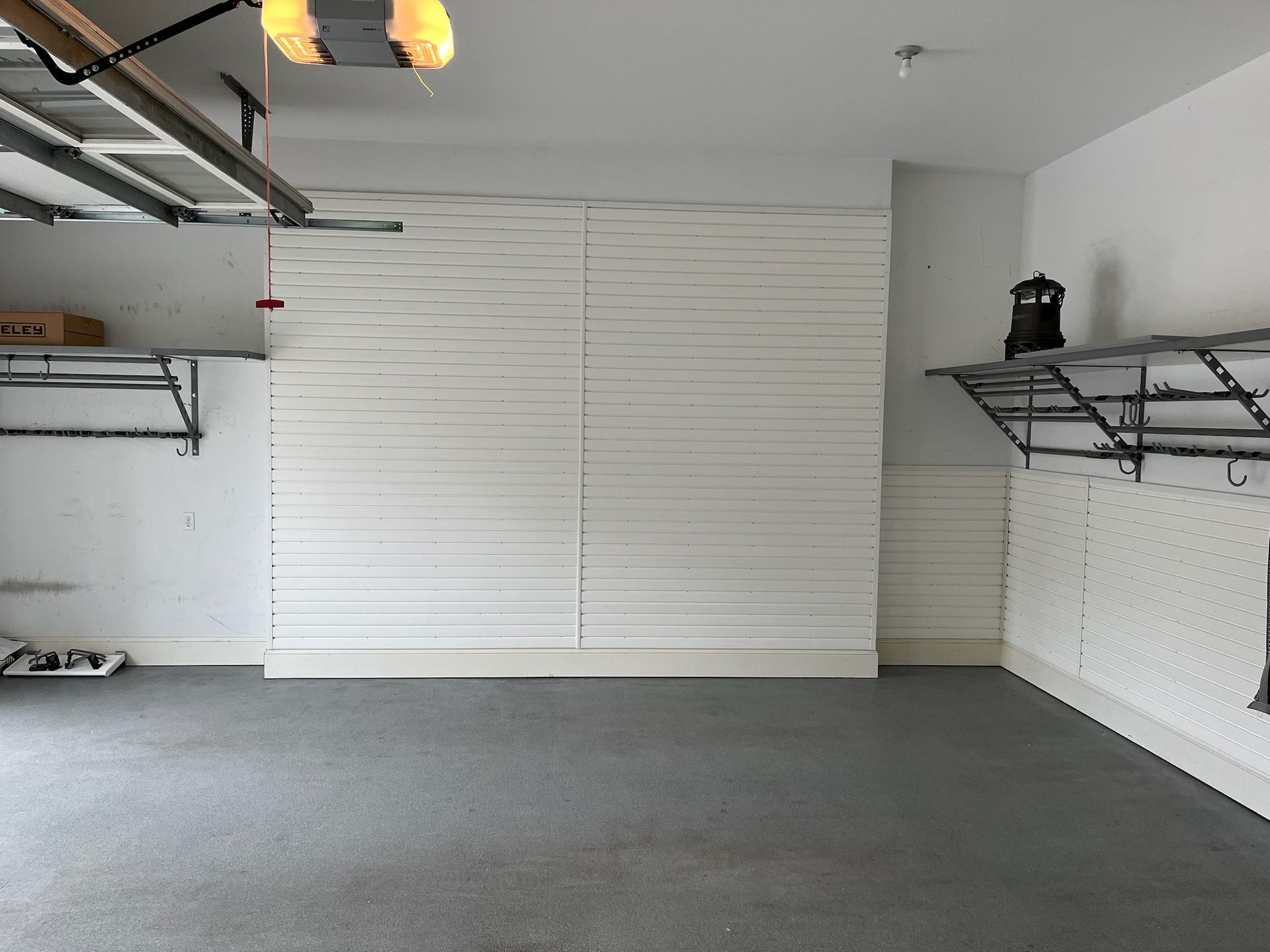 Empty garage with gray floor, white walls, and metal storage shelves on both sides