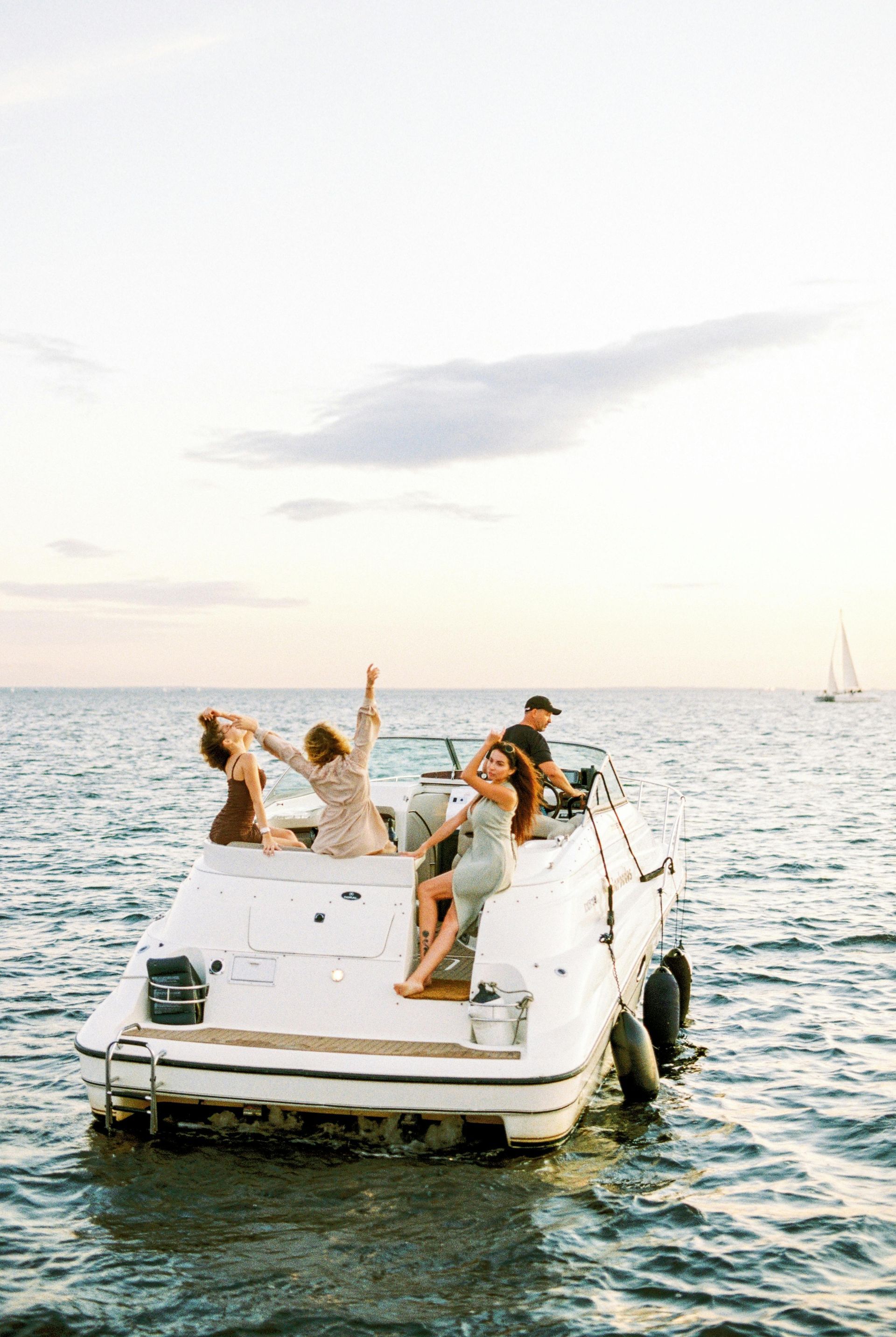 People relaxing on a small white boat at sea during sunset.