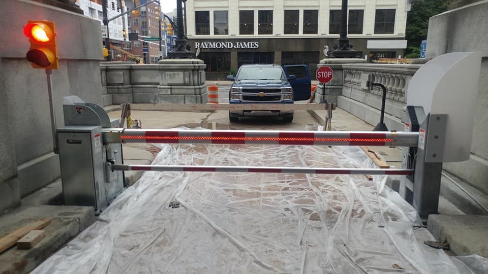Snow-covered parking barrier with a red-and-white gate blocking a car at an entrance.