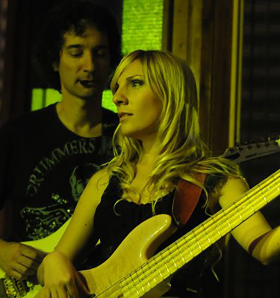 a lady with a guitar and a man standing behind her