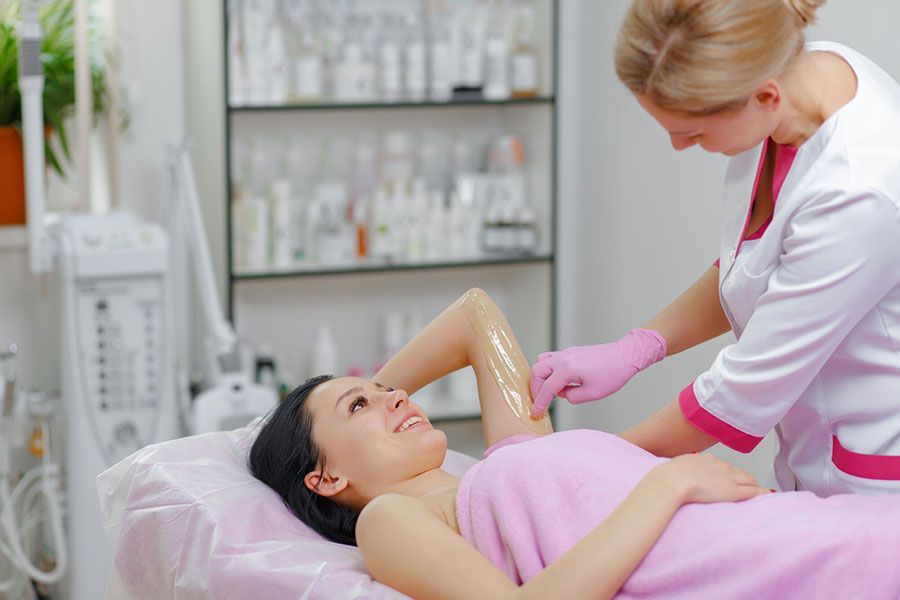 Spa technician applying treatment to a woman lying on a treatment bed
