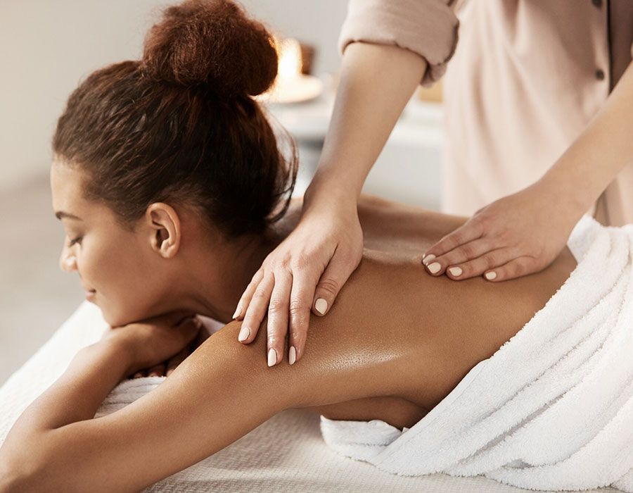 Person receiving a back massage on a spa table with white towels