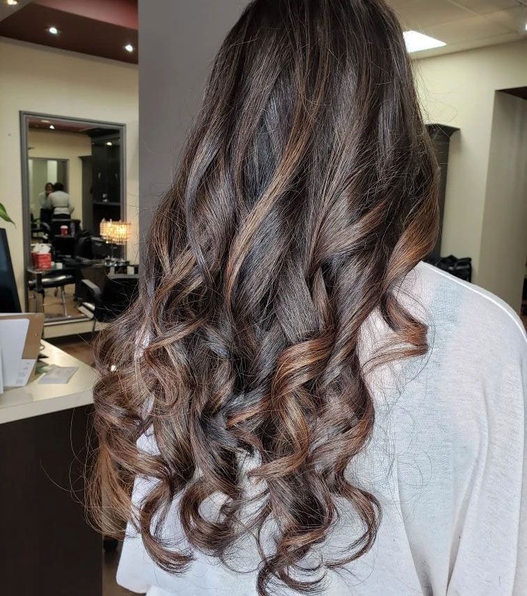 Long, curly brown hair viewed from behind in a salon mirror