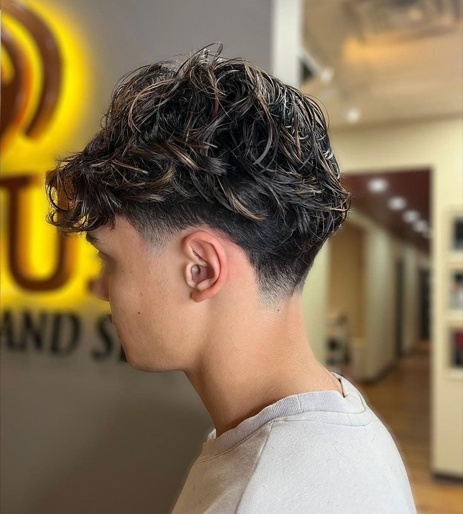 Profile view of a curly textured fade haircut in a salon interior