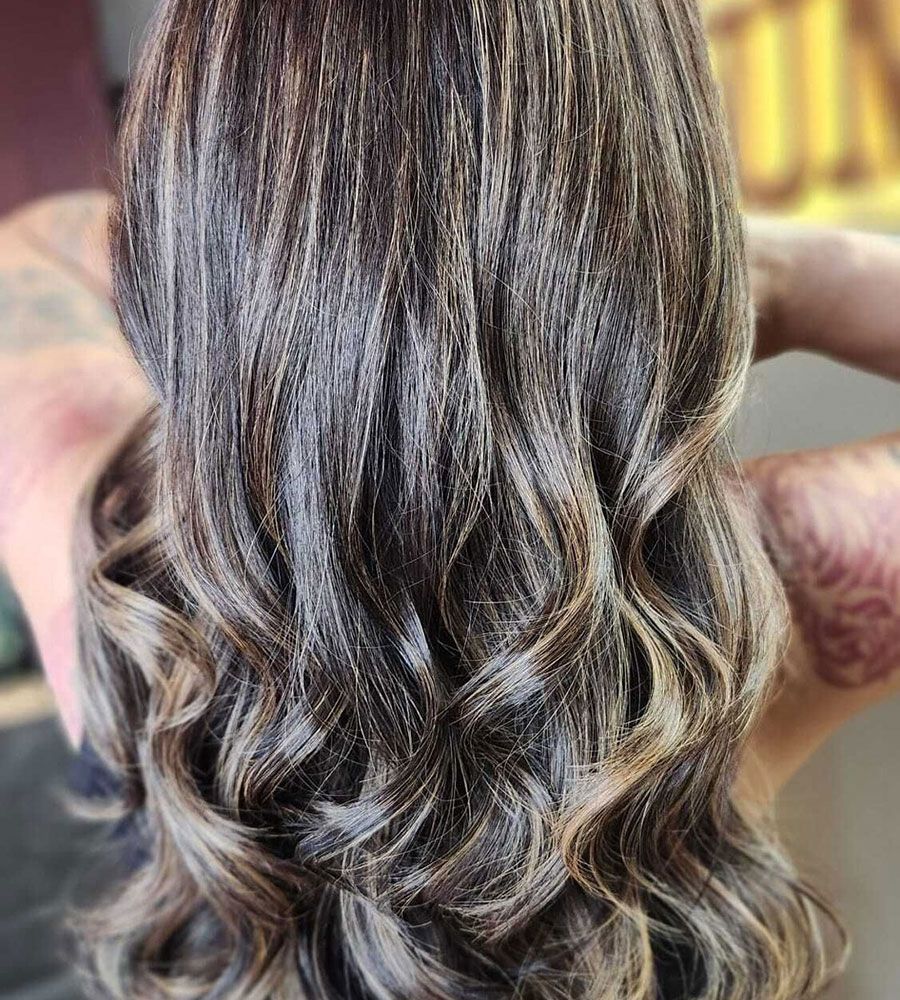 Wavy brown hair with blonde highlights cascading down the back