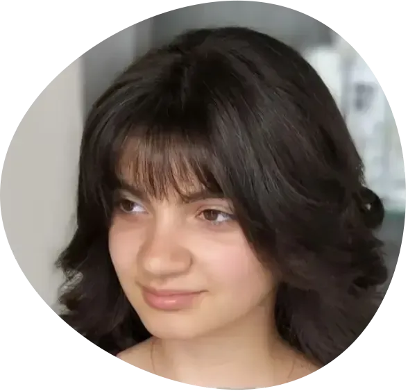 Portrait of a person with dark wavy hair and bangs, looking slightly to the side with a neutral expression
