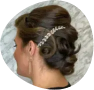 Dark brown updo with pearl hair accessory, side profile against a light textured background