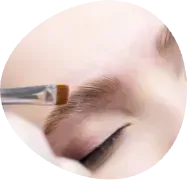 Makeup brush applying eyebrow makeup to a closed eye