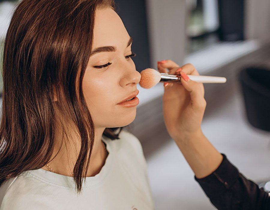 Makeup artist applying blush to a woman’s face with a brush