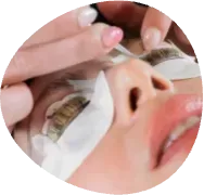 Close-up of eyelash extensions being applied to a person’s eye with tweezers