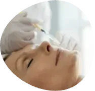 Close-up of a person receiving a facial injection with a syringe in a clinical setting