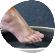 Foot pressing into a shallow black basin of water, creating ripples
