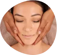 Woman receiving facial massage with eyes closed and hands framing her face