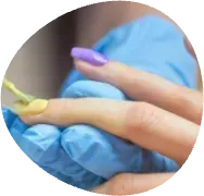 Gloved hand holding a small green plant sprout near a finger with a nail brush, close-up