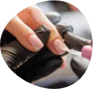 Hands filing a fingernail with a pink nail file and black nail polish bottle nearby
