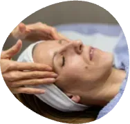 Person receiving a facial massage with a white headband, eyes closed, in a spa setting