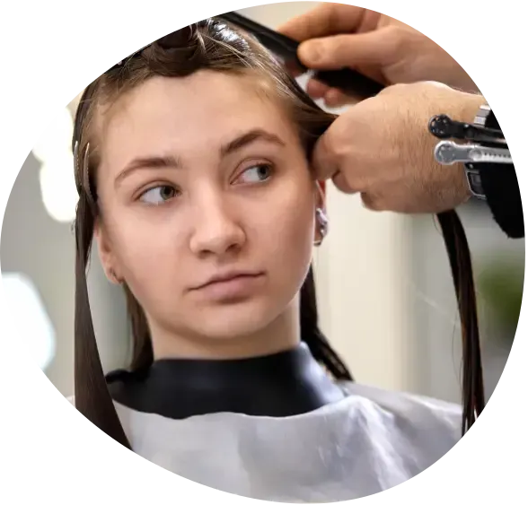 Stylist cutting a woman’s hair with scissors in a salon