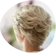 Short blonde layered haircut seen from the back against a soft blurred background