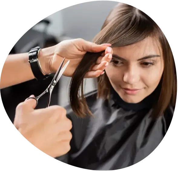 Hairdresser trimming a woman’s bangs with scissors in a salon