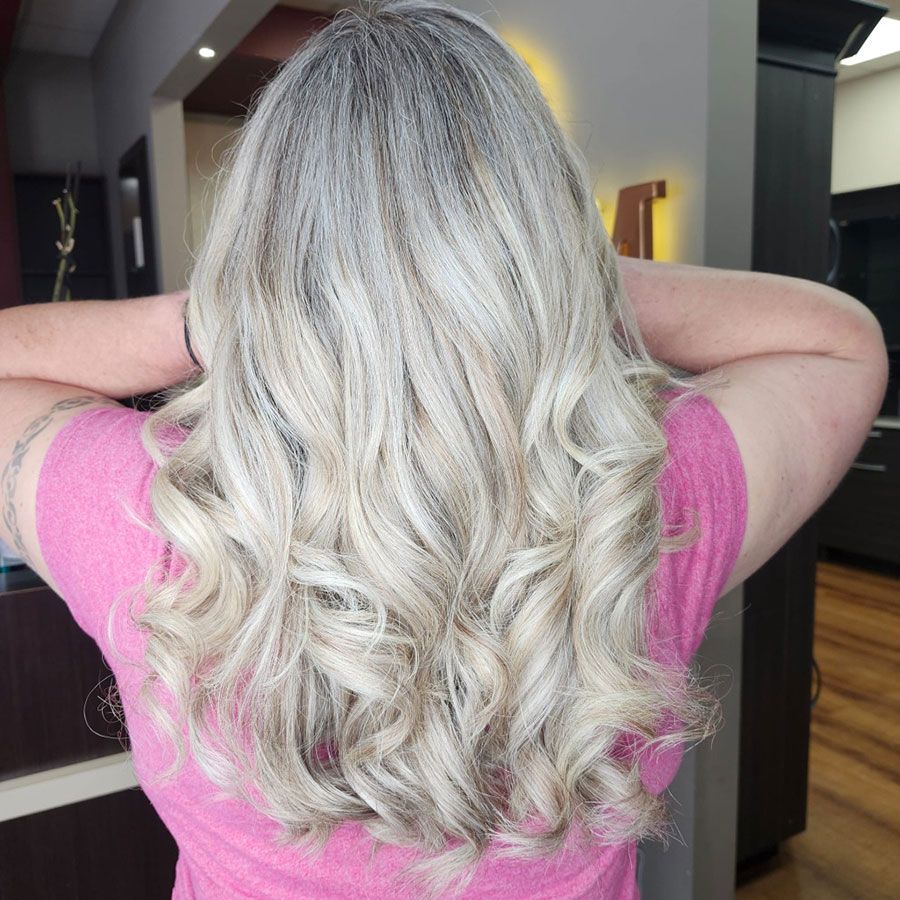 Back view of long wavy platinum-blonde hair worn loose in a salon