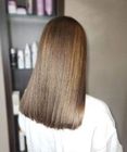 Back view of shoulder-length straight brown hair with subtle highlights in a salon setting
