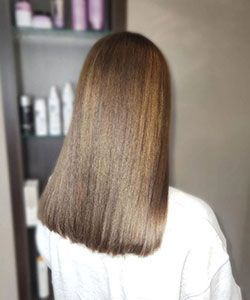 Back view of shoulder-length straight brown hair with subtle highlights in a salon setting