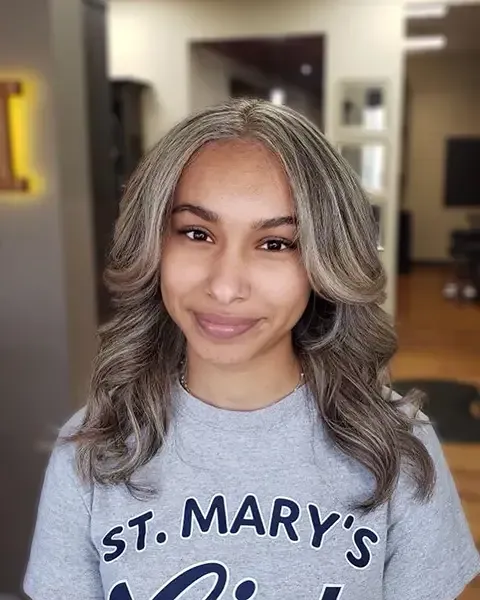 Person with gray hair wearing a gray "St. Mary's" shirt, smiling indoors.