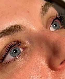 Close-up of blue eyes and freckles with mascara, looking upward