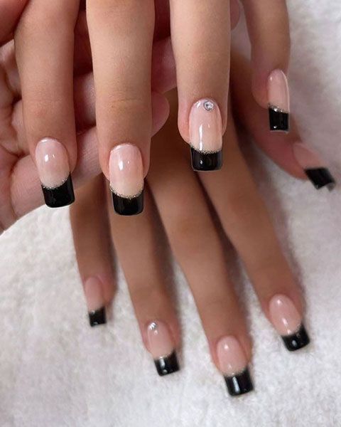 Close-up of hands with nude pink nails and black French tips on a white textured background