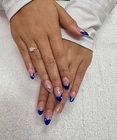 Hands with blue French-tip nails and a ring resting on a white towel