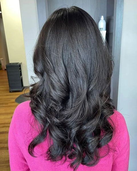 Back view of shoulder-length wavy dark hair with soft curls, wearing a bright pink top