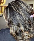 Layered wavy brown hair with blonde highlights, styled in a salon close-up.