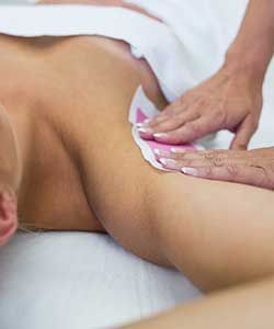 Hands wiping oil on a person's shoulder during a massage