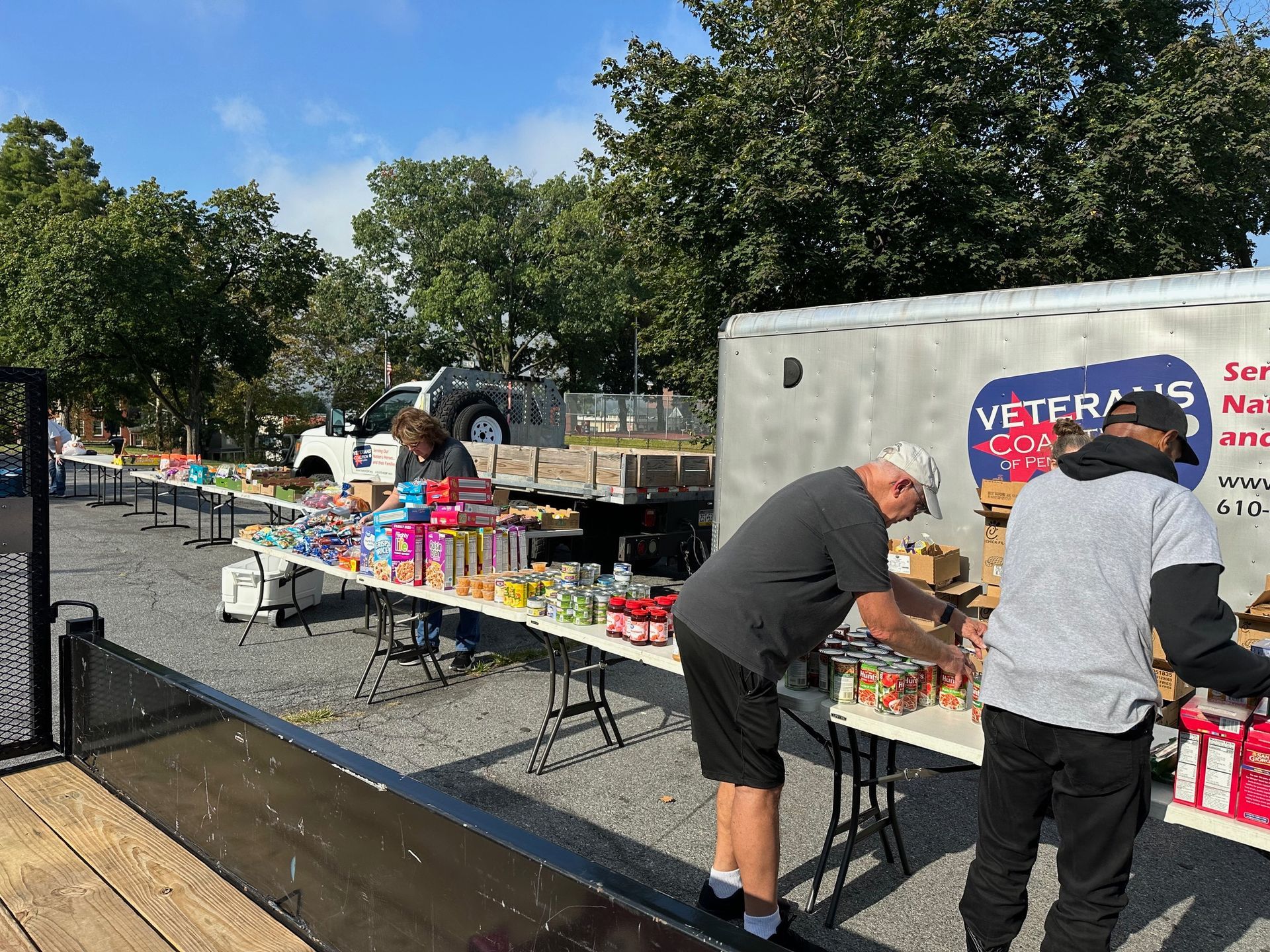 Volunteers sort food items at an outdoor Veterans food distribution event.