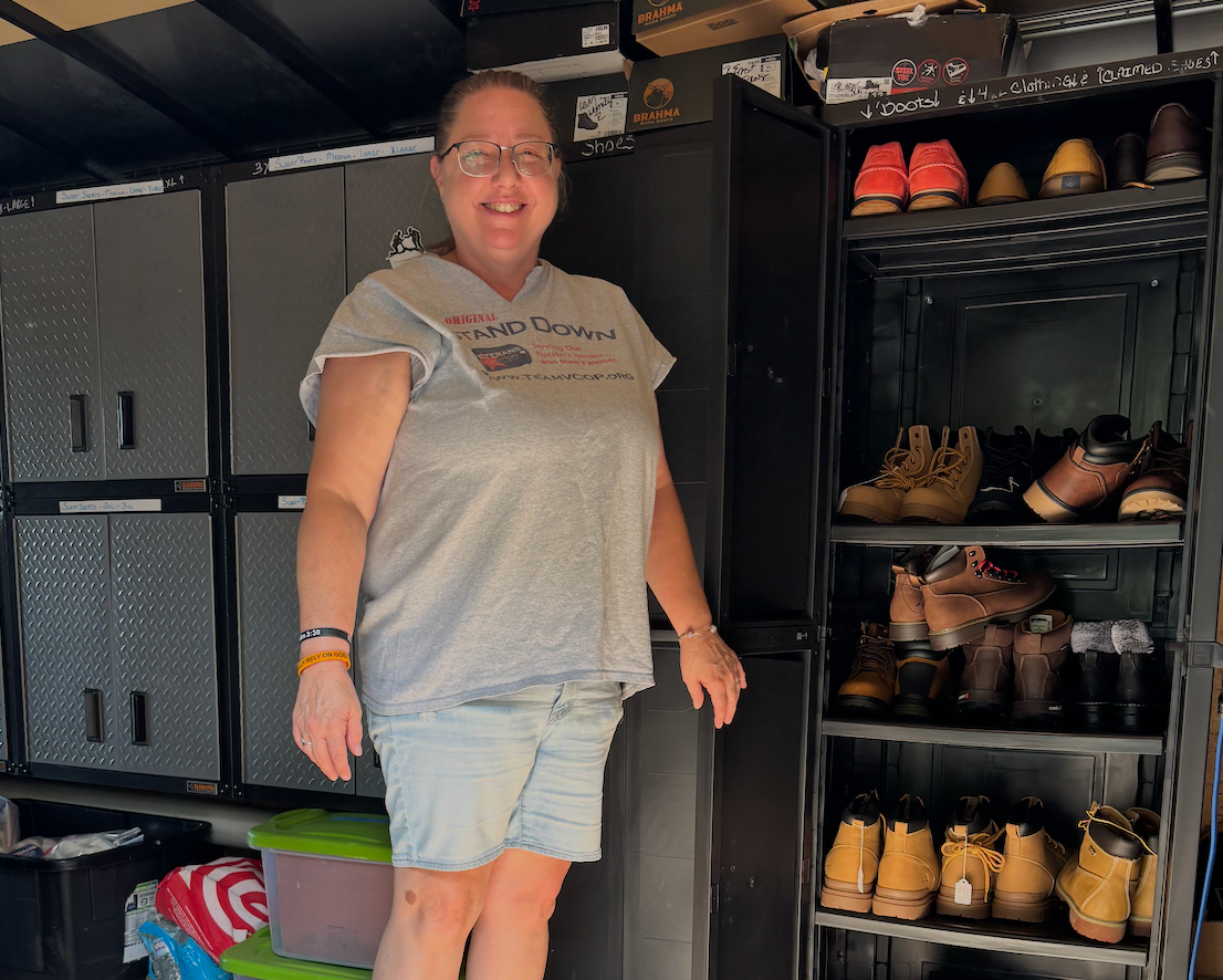 Woman smiles in garage, standing near black storage cabinets and a shoe rack with various shoes.
