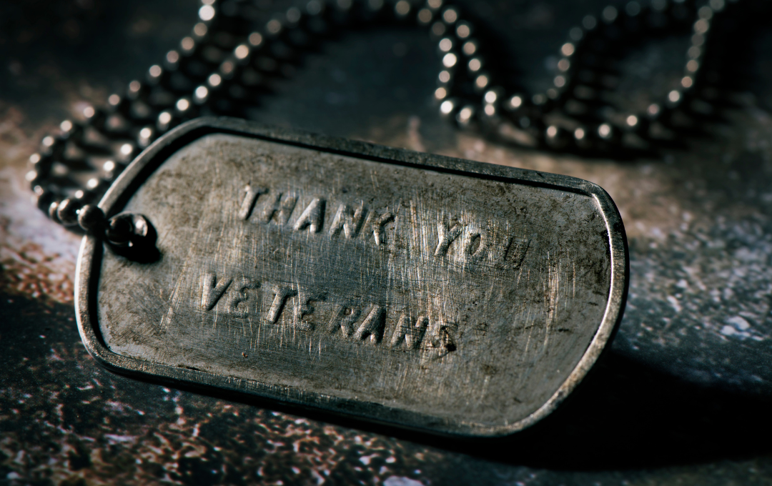 Close-up of a weathered military dog tag on a chain, engraved with 
