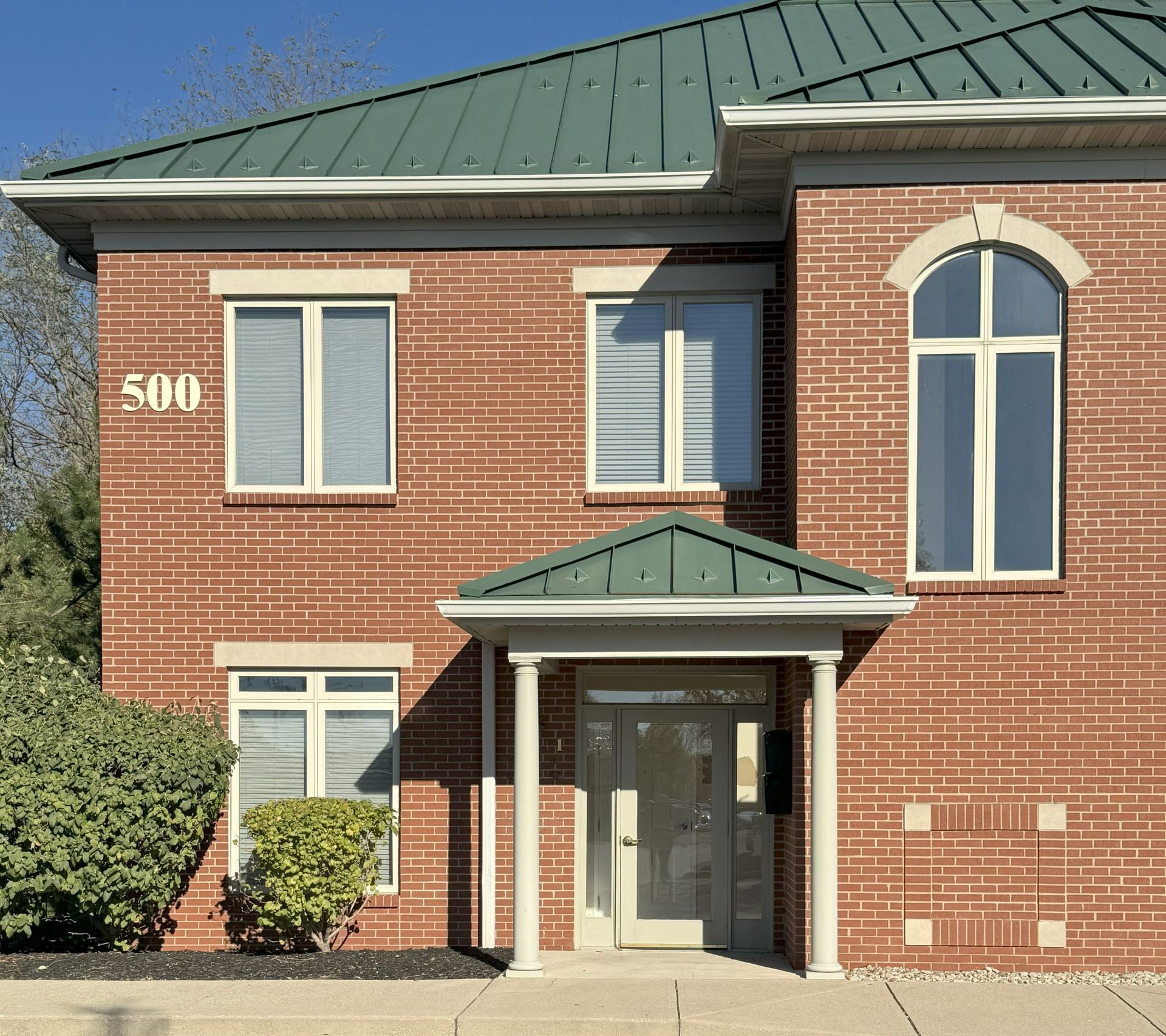 Two-story brick building with green roof, columns at entrance; address 500.