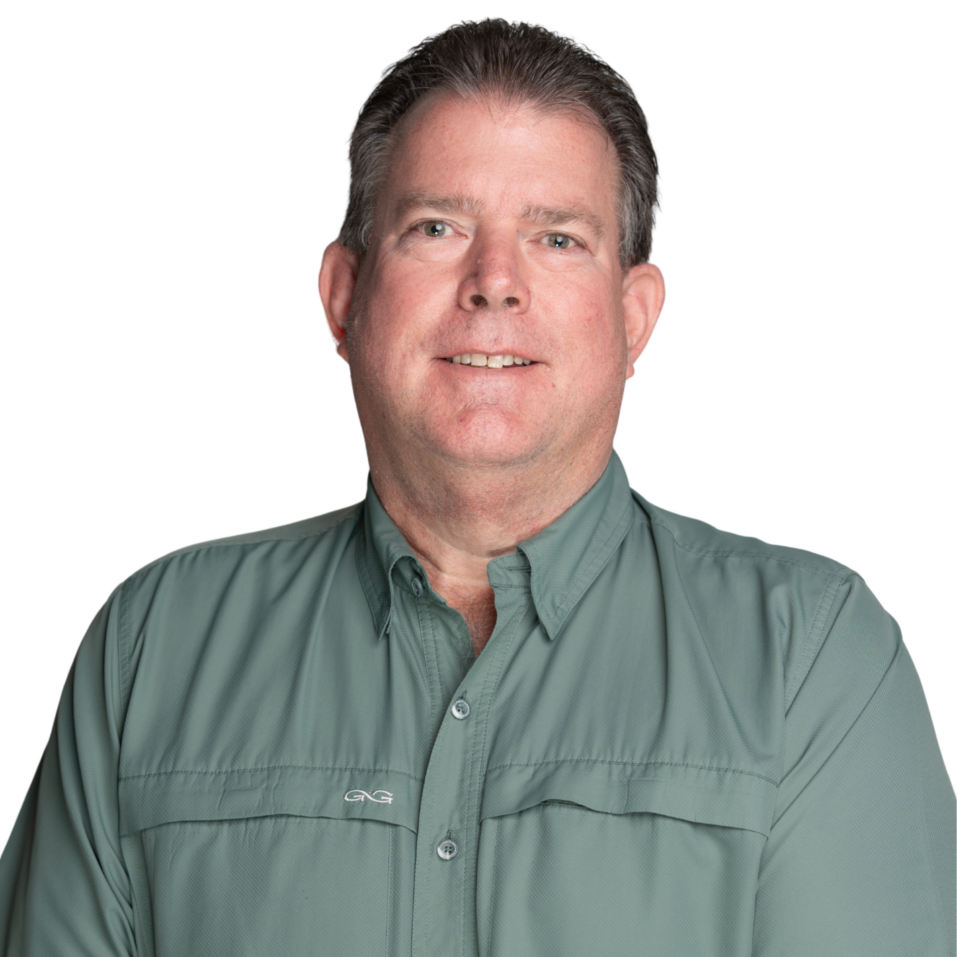 Man with short hair, smiling, wearing a green collared shirt, leaning against a tree.