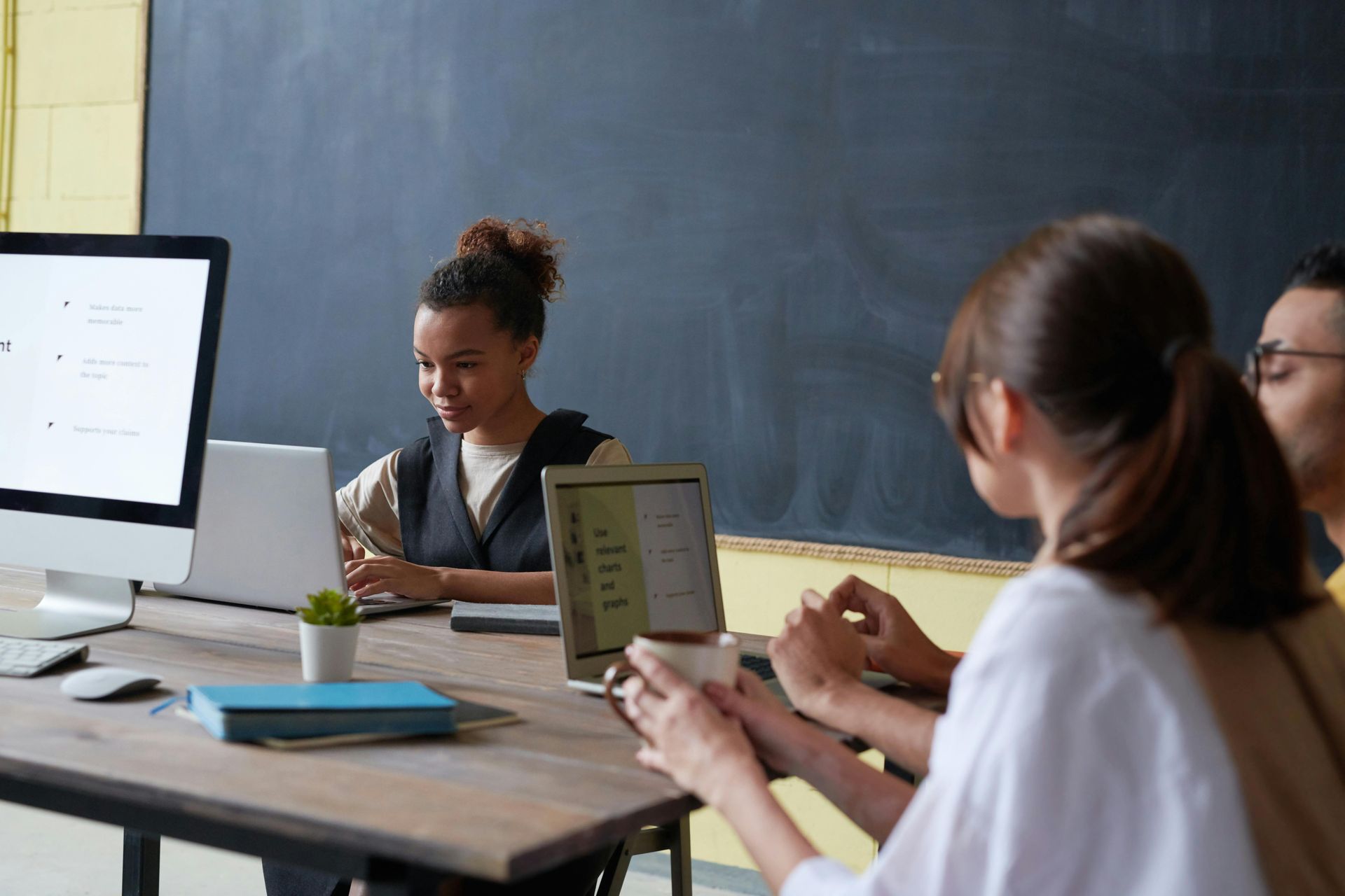 A group of people are sitting around a table with computers and laptops.